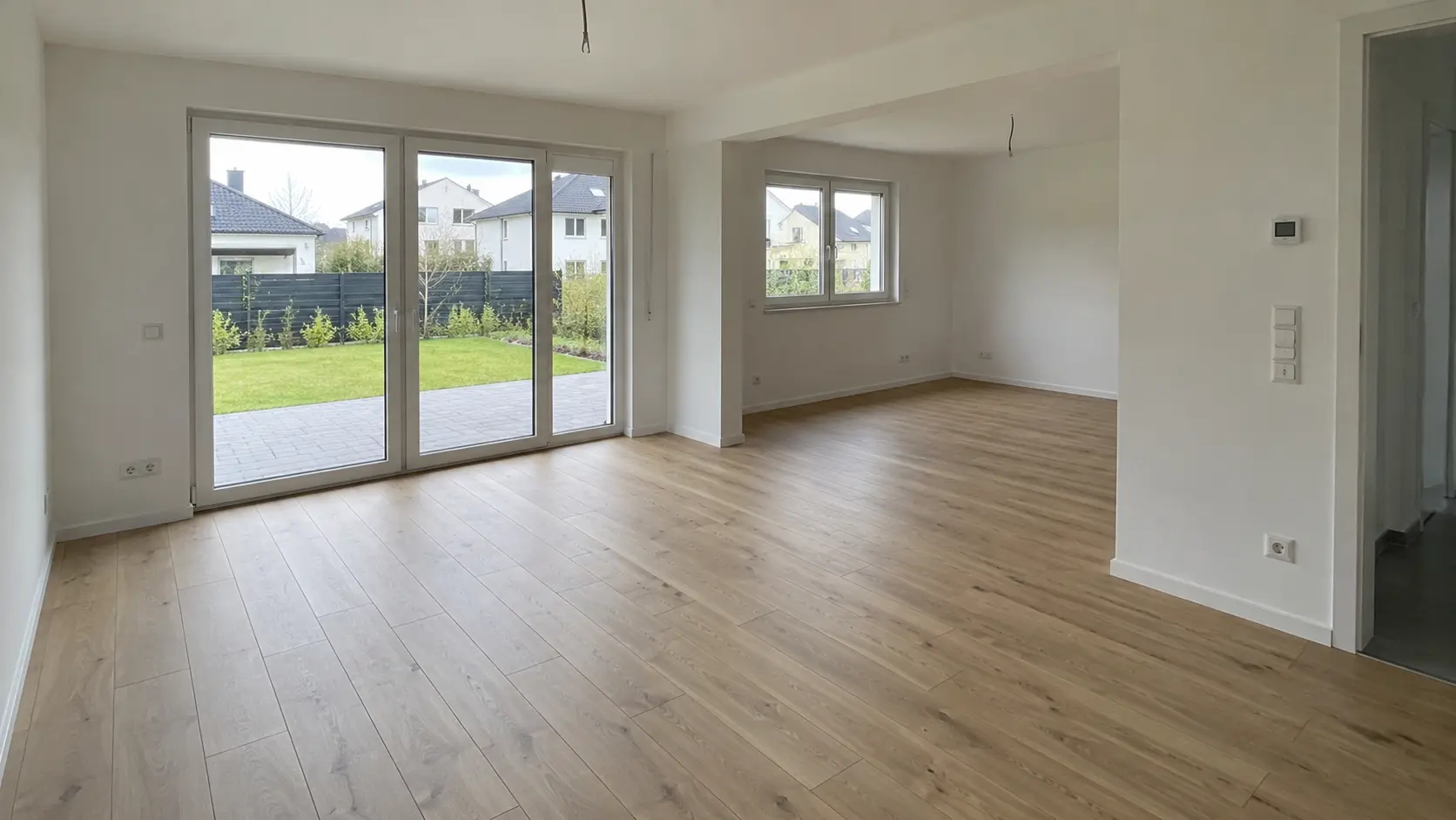 Leerer Wohn- und Essbereich mit großer Glastür zur Terrasse und zum Garten