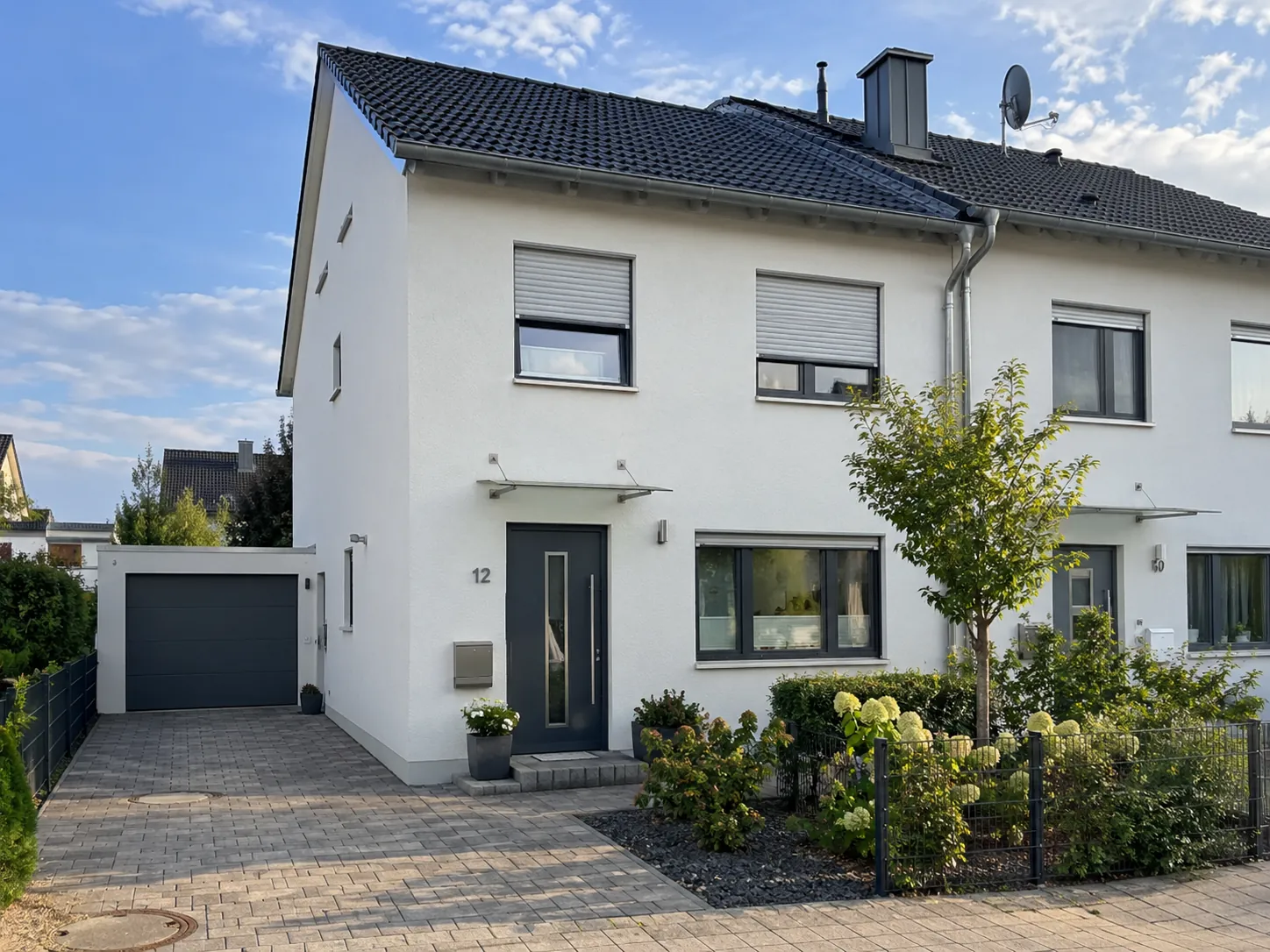 Weiße Doppelhaushälfte mit Garage, Vordach und gepflegtem Vorgarten