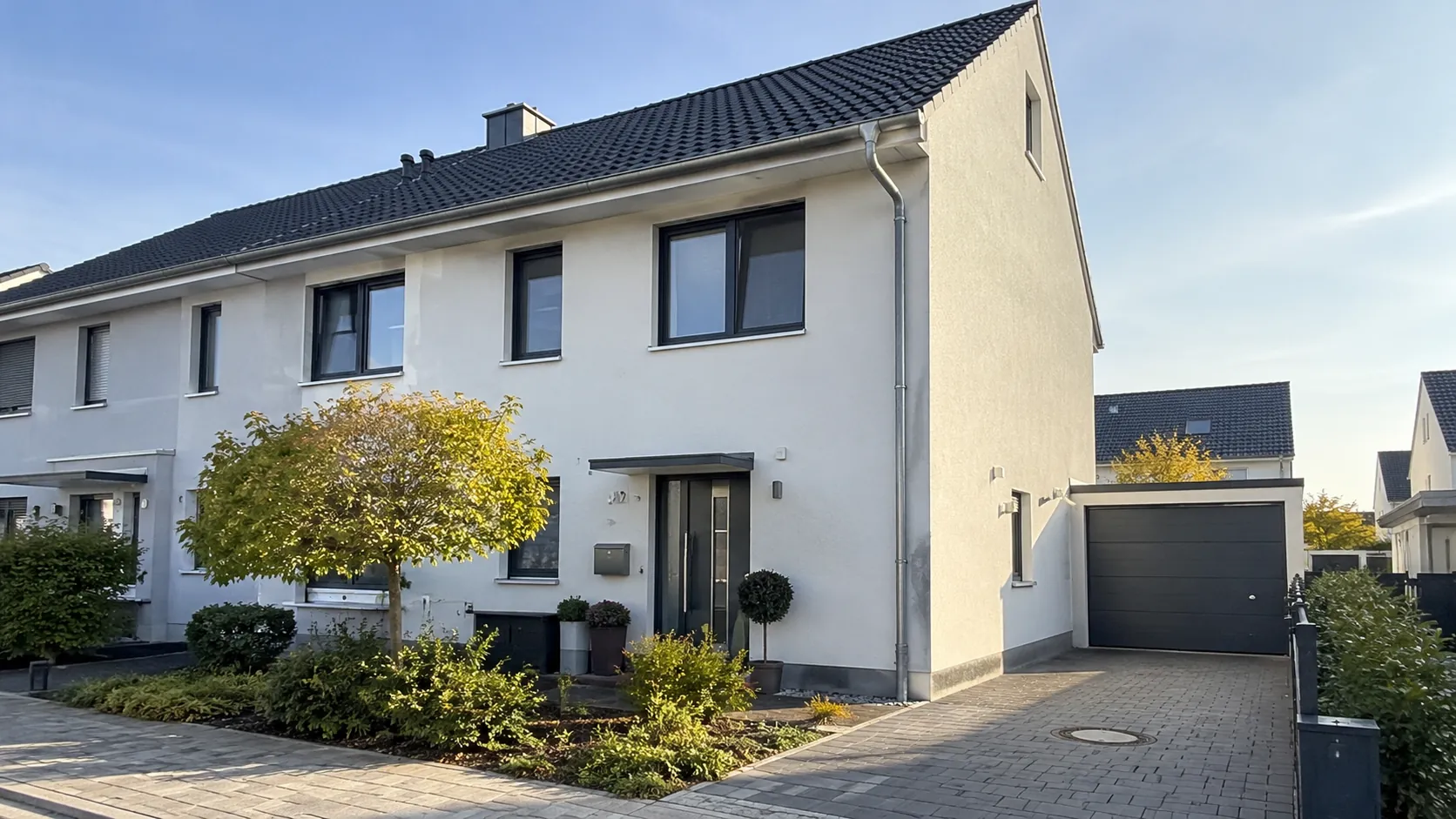 Reihenendhaus mit Garage und bepflanztem Vorgarten in der Abendsonne